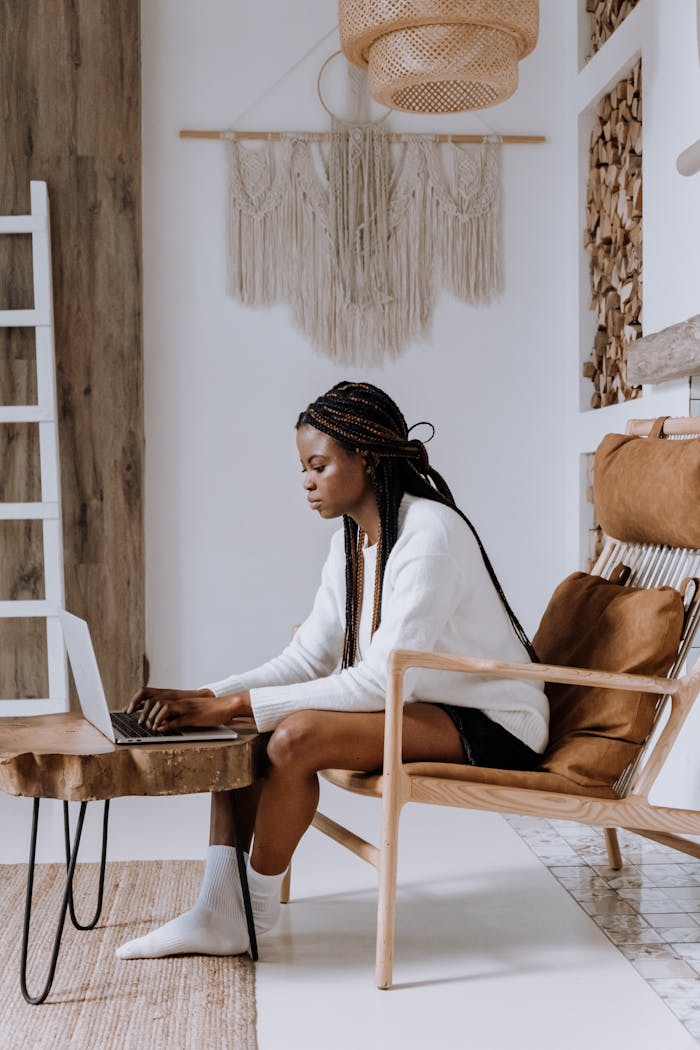 African American woman using a laptop in a cozy, modern Scandinavian-style apartment.